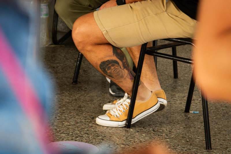 En los colegios se apreciaba una variada gama de elementos; un tatuaje de Diego Maradona emerge, evocando la nostalgia y la esperanza, mientras acompaña a la democracia en este día.