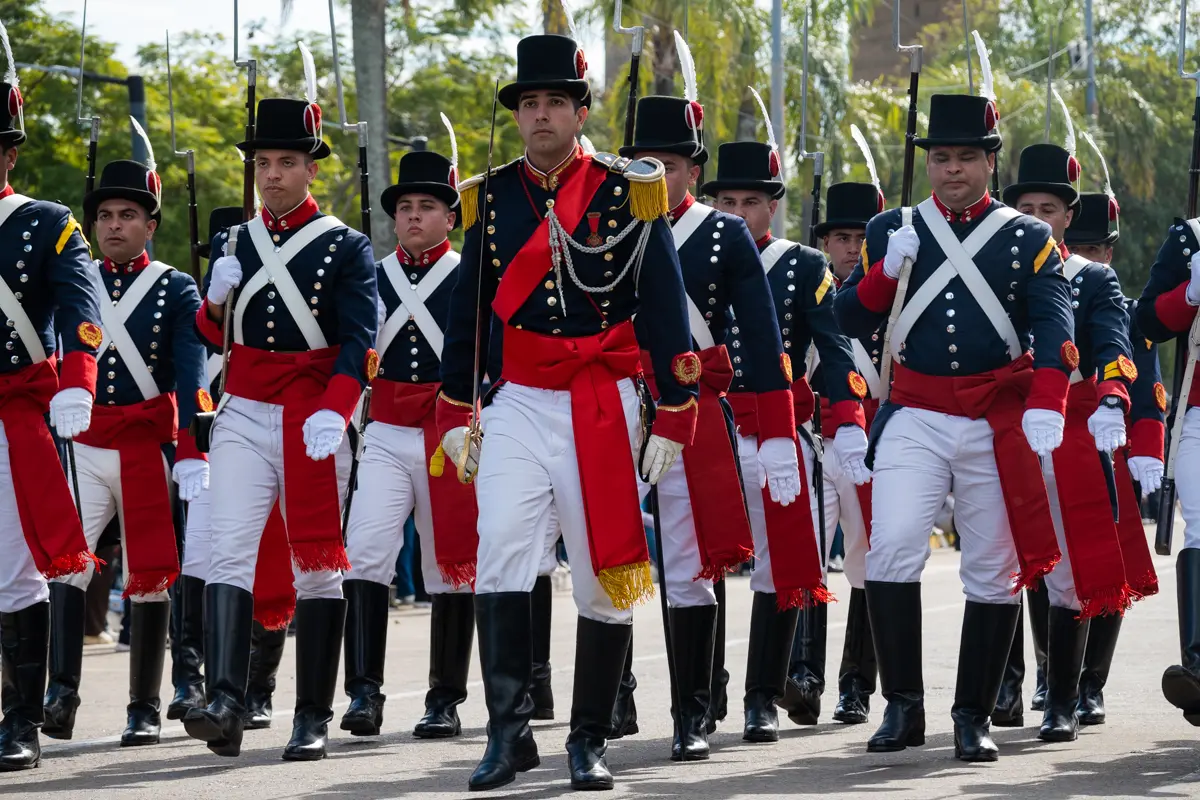 La formaci&oacute;n de uniformes hist&oacute;ricos desfil&oacute; con paso ceremonial, recuperando una est&eacute;tica vinculada a las primeras tropas nacionales. El contraste entre las prendas de &eacute;poca, las marchas y el paisaje urbano acerc&oacute; una referencia del pasado al presente de la celebraci&oacute;n.
