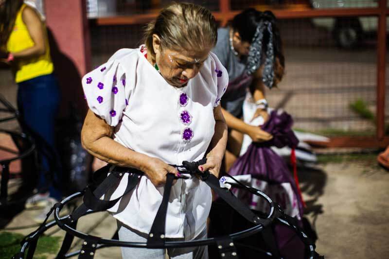 Bajo la tenue luz de los postes documentamos cómo, en cuestión de minutos, se transformaron con trajes vibrantes de verde, morado y naranja. Los trajes, a pesar de ser voluminosos, fueron hechos con creatividad, ofreciendo confort y facilidad. 