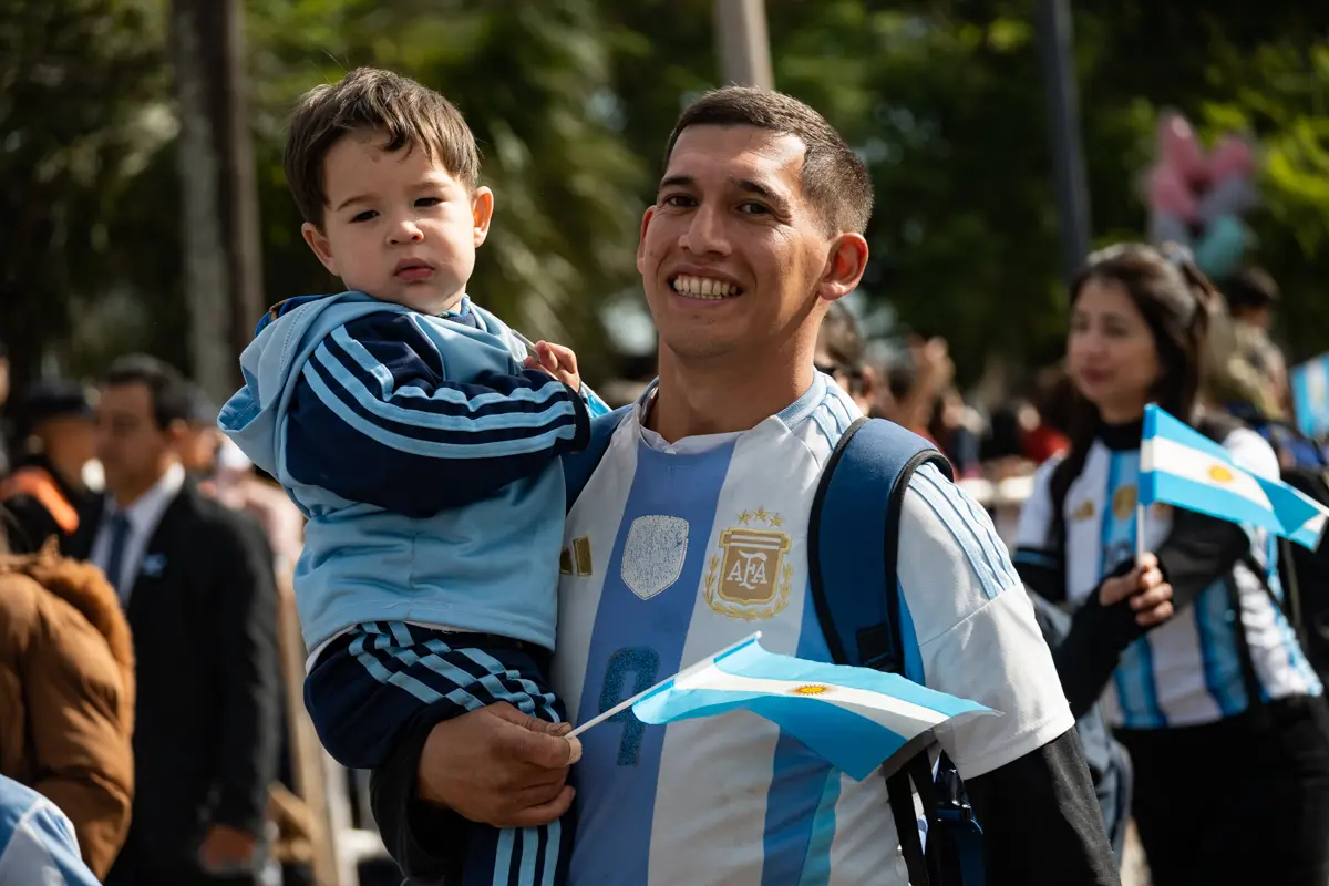 Entre el p&uacute;blico, un padre y su hijo siguieron el desfile con camisetas argentinas y una peque&ntilde;a bandera. La escena condens&oacute; el car&aacute;cter familiar de una celebraci&oacute;n que reuni&oacute; generaciones alrededor de la Costanera General San Mart&iacute;n
