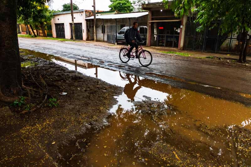 Un trabajador se dirige a realizar sus tareas en bicicleta, un sencillo transporte que no genera complicaciones, pero que presenta problemas para quien conduce, salpicado y enlodado, por las calles de barro.