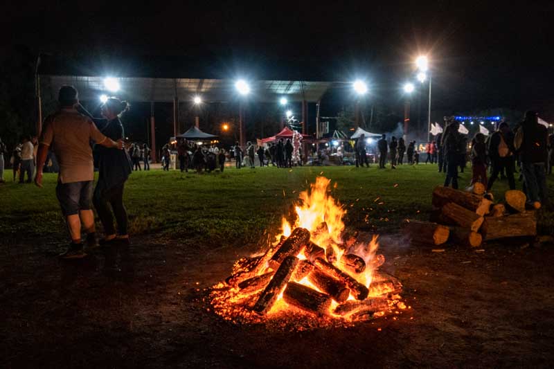 La celebración atrae a una multitud de personas que se reúnen alrededor del fuego, participando activamente y sintiendo la energía comunitaria que emana de las llamas.