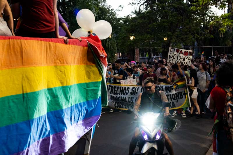 Una motocicleta iluminó una gran bandera arcoíris mientras la noche caía sobre la ciudad, cerrando uno de los últimos tramos del recorrido.