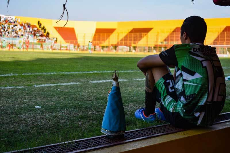 La imagen de la patrona de Corrientes se encuentra de frente a la cancha, acompañando al equipo en su jornada futbolística. La espiritualidad y la creencia en un poder superior se entrelazan con el deporte, brindando una atmósfera única y significativa durante el enfrentamiento.