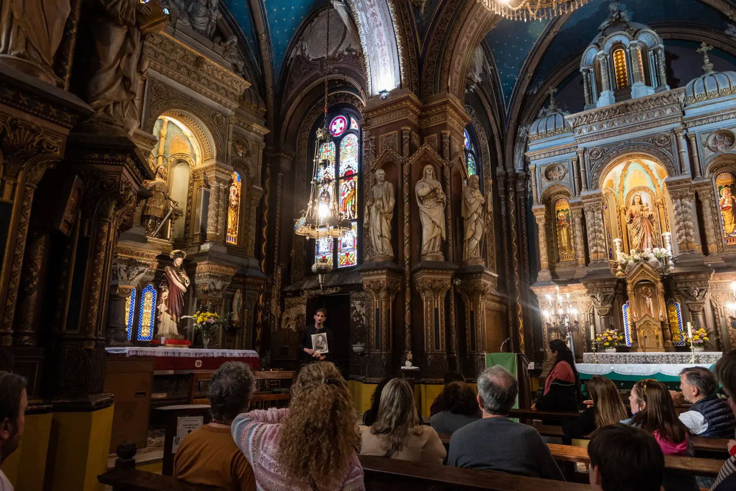 La nave central conduce la mirada hacia el altar y re&uacute;ne distintos elementos que fueron pensados como parte de un espacio destinado a conservar la memoria de Felicitas. La composici&oacute;n interior combina ornamentaci&oacute;n, vitrales, pinturas y detalles decorativos.
