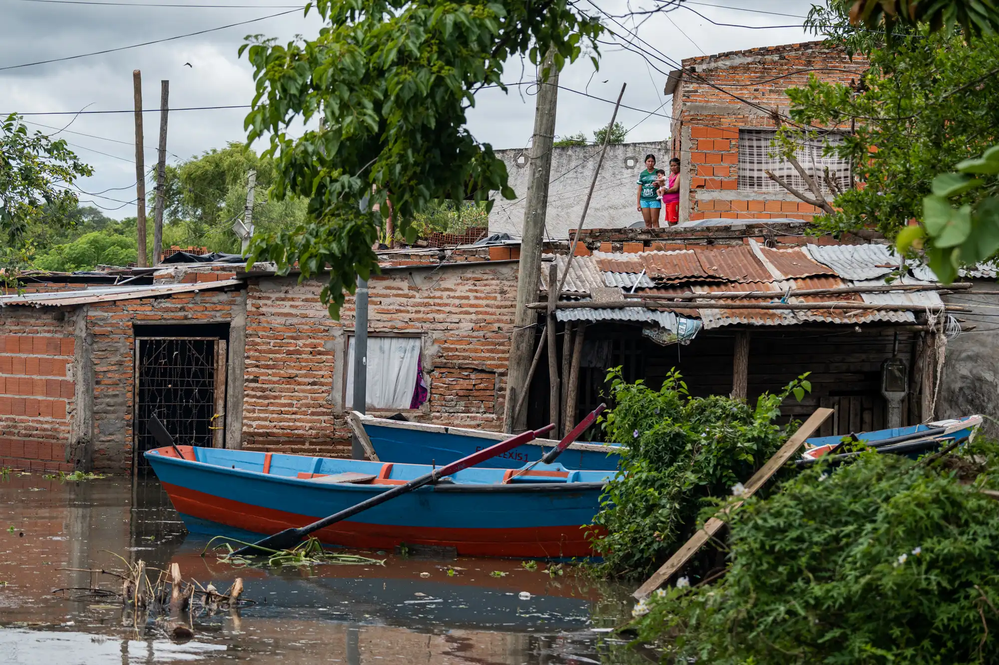 La ayuda no termina donde acaba el camino. Algunas familias permanecen en las plantas altas de sus viviendas, mientras el agua cubre los niveles inferiores e impide salir por tierra. Hasta allí llegan otros vecinos en canoa, llevando comida y acercando lo necesario para atravesar el día. La misma organización que recibe donaciones, prepara los alimentos y los reparte se ocupa también de quienes permanecen rodeados por el agua.